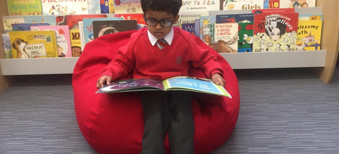boy reading whilst sat on a red beanbag